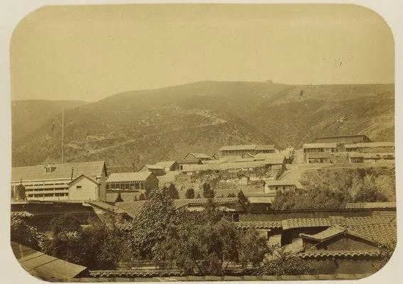 Panoramica sepia de un poblado chileno de cerro con casas de tejado y quebrada — aprox. 1890–1930 | Chile de Ayer