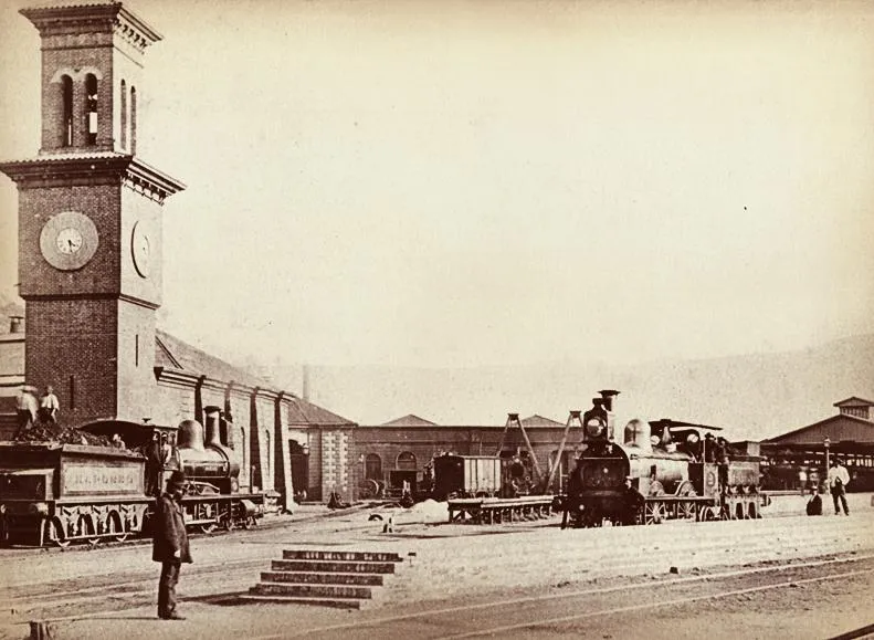 Estación ferroviaria con torre de reloj y locomotoras a vapor — aprox. 1890–1930 | Chile de Ayer