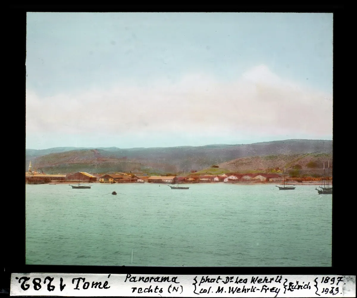 Panorama norte de Tome desde el mar, galpones junto a la playa y veleros en la bahia — aprox. 1897–1940 | Chile de Ayer