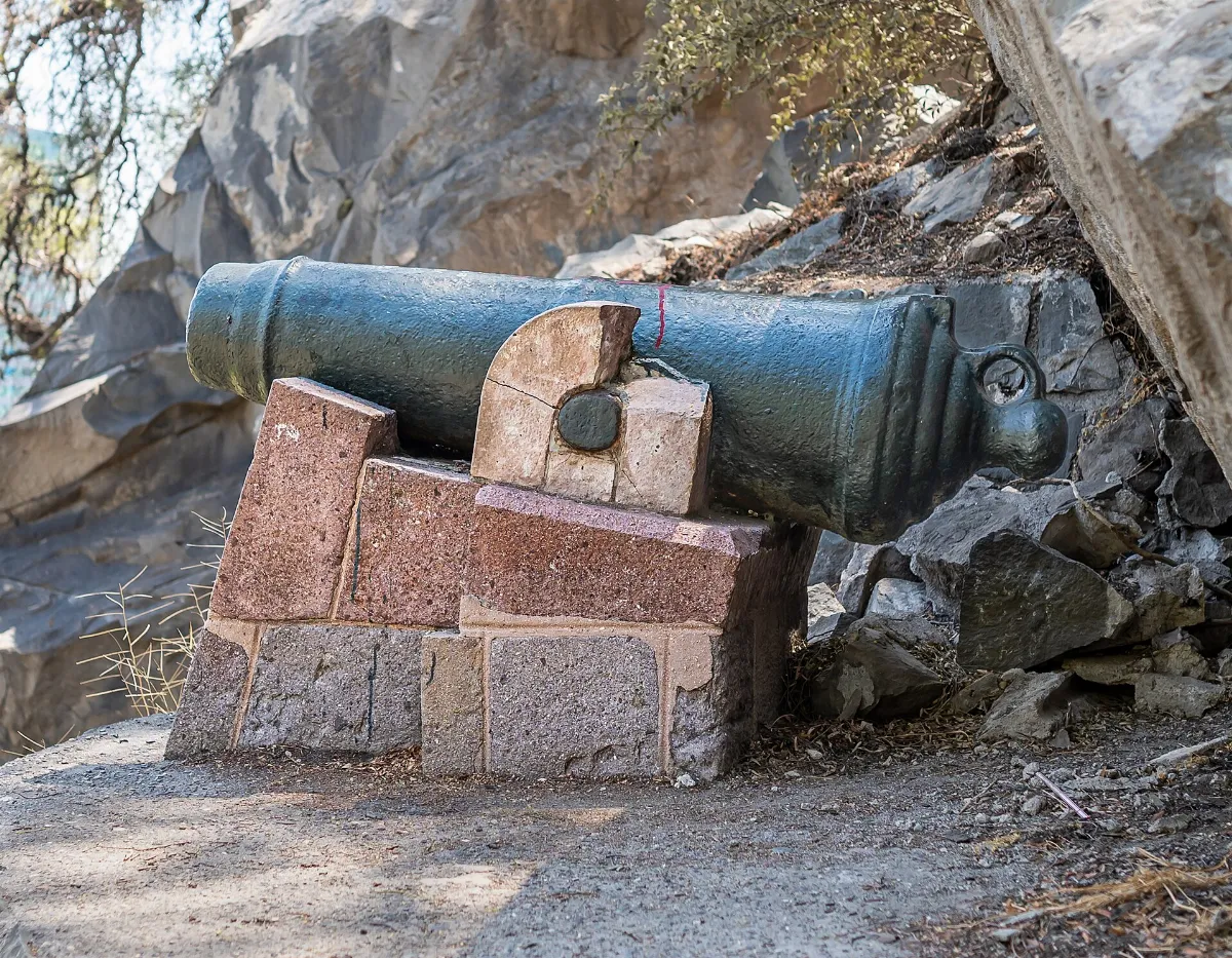 Cañón colonial de bronce sobre pedestal de piedra junto a la roca del Cerro Santa Lucía — aprox. 1880–1930 | Chile de Ayer