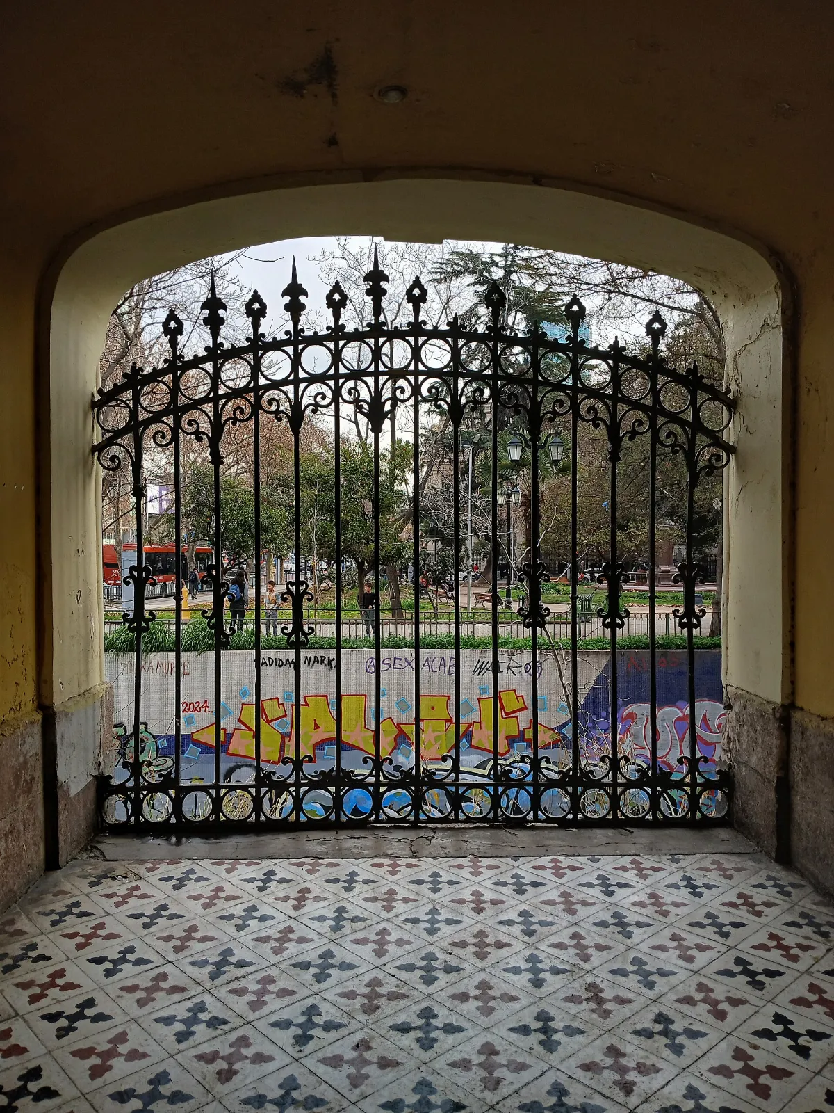 Puerta de acceso al Cerro Santa Lucía con vista a plaza arbolada — aprox. 1880–1930 | Chile de Ayer