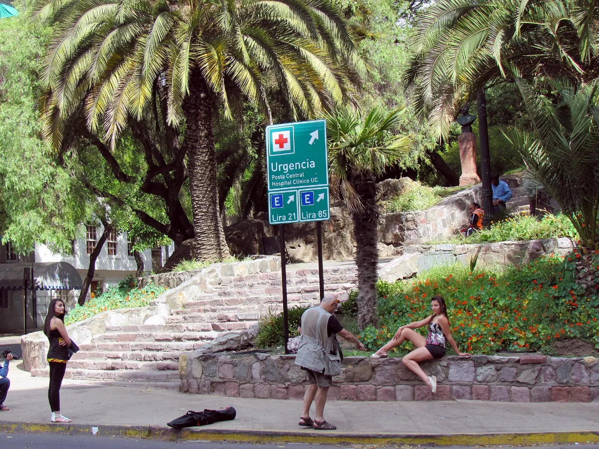 Entrada al Cerro Santa Lucía con señalética de urgencia y peatones en la vereda — aprox. 1880–1930 | Chile de Ayer