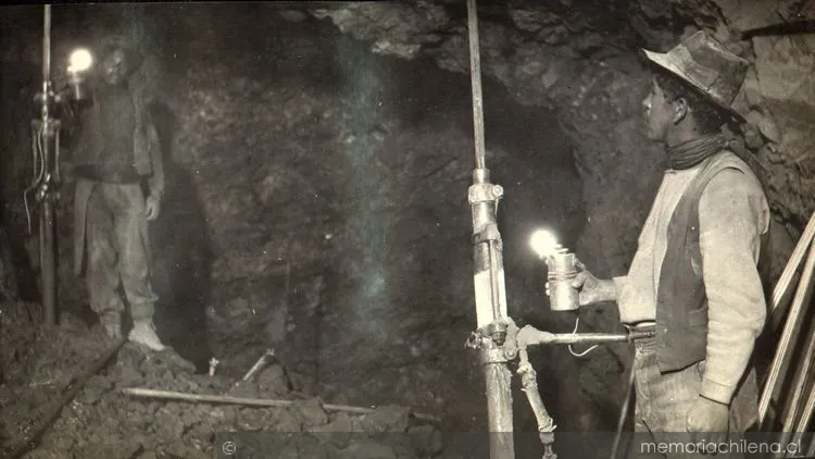 Dos mineros trabajan al interior de la mina con sus jacklegs o perforadoras, hacia 1915 — 1915 | Chile de Ayer