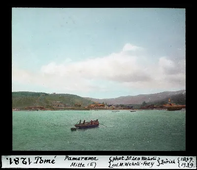Panorama central de Tome con bote a remo y caserio costero, diapositiva coloreada de 1897 — aprox. 1897–1940 | Chile de Ayer