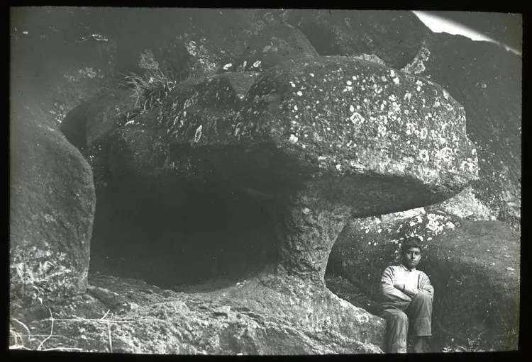 Chilean boy sitting underneath the sculpture, for scale; Rano Raraku, Oc,G.T.1644, Mana Expedition to Easter Island, British Museum — Isla de Pascua — 1914 | Chile de Ayer