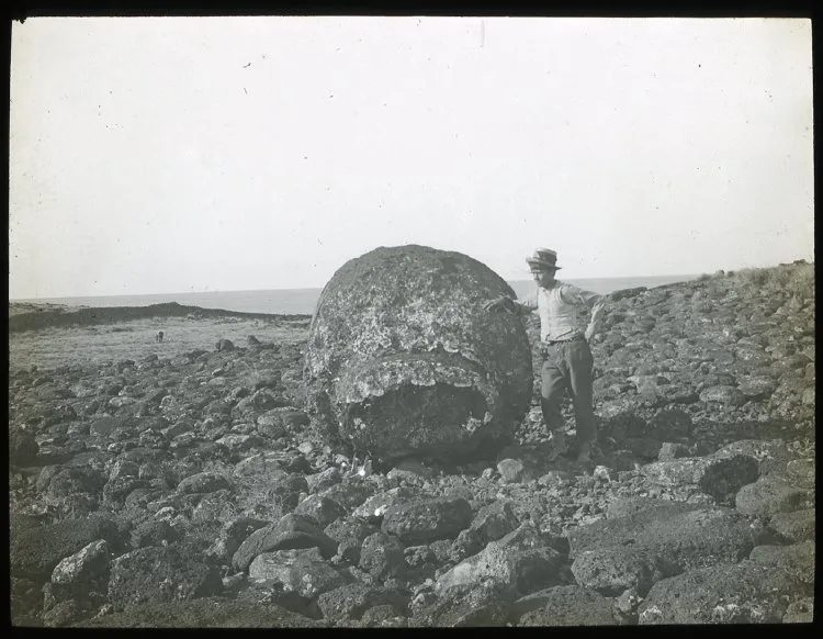 Chilean boy standing beside a large round stone used as part of a moai; Ahu Hekii, Oc,G.T.1623, Mana Expedition to Easter Island, British Museum — Isla de Pascua — 1914 | Chile de Ayer