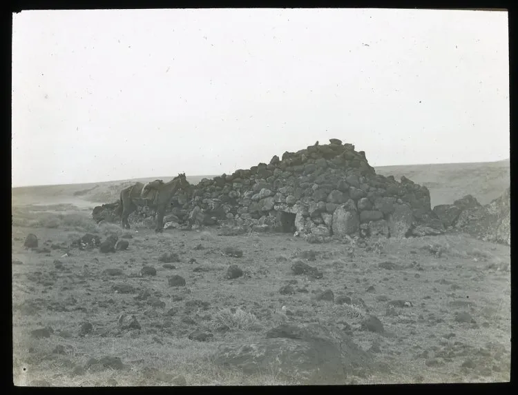 View of an ahu structure, made into a pyrramidal shaped house made from stones and with an entrance in the centre; a horse on the left, for scale; Hotu Iti(?), Oc,G.T.1622, Mana Expedition to Easter Island, British Museum — Isla de Pascua — 1914 | Chile de Ayer