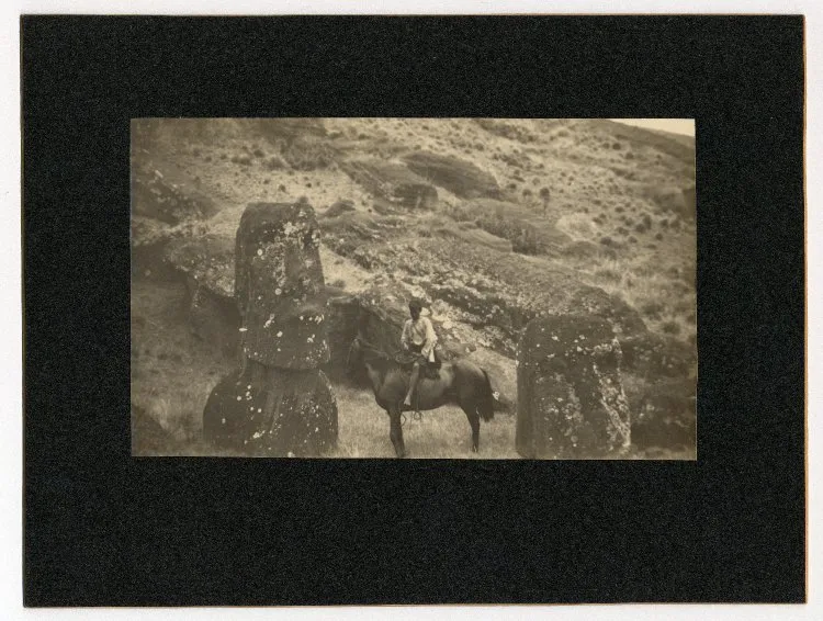 View of hill, with two moai (stone figure carving heads) visible; a boy sitting on a horse in between both sculptures; Rano Raraku, Oc,B30.11, Mana Expedition to Easter Island, British Museum — Isla de Pascua — 1914 | Chile de Ayer