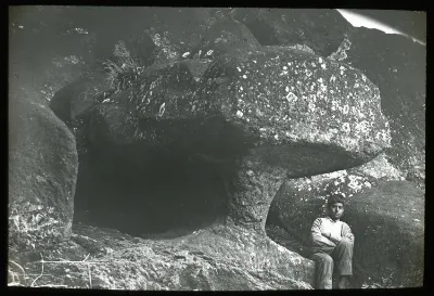 Chilean boy sitting underneath the sculpture, for scale; Rano Raraku, Oc,G.T.1644, Mana Expedition to Easter Island, British Museum — Isla de Pascua — 1914 | Chile de Ayer