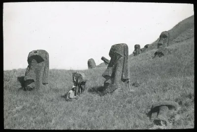 Polynesian(?) man sitting on the ground with a horse next to partially buried moai; Rano Raraku, Oc,G.T.1608, Mana Expedition to Easter Island, British Museum — Isla de Pascua — 1914 | Chile de Ayer