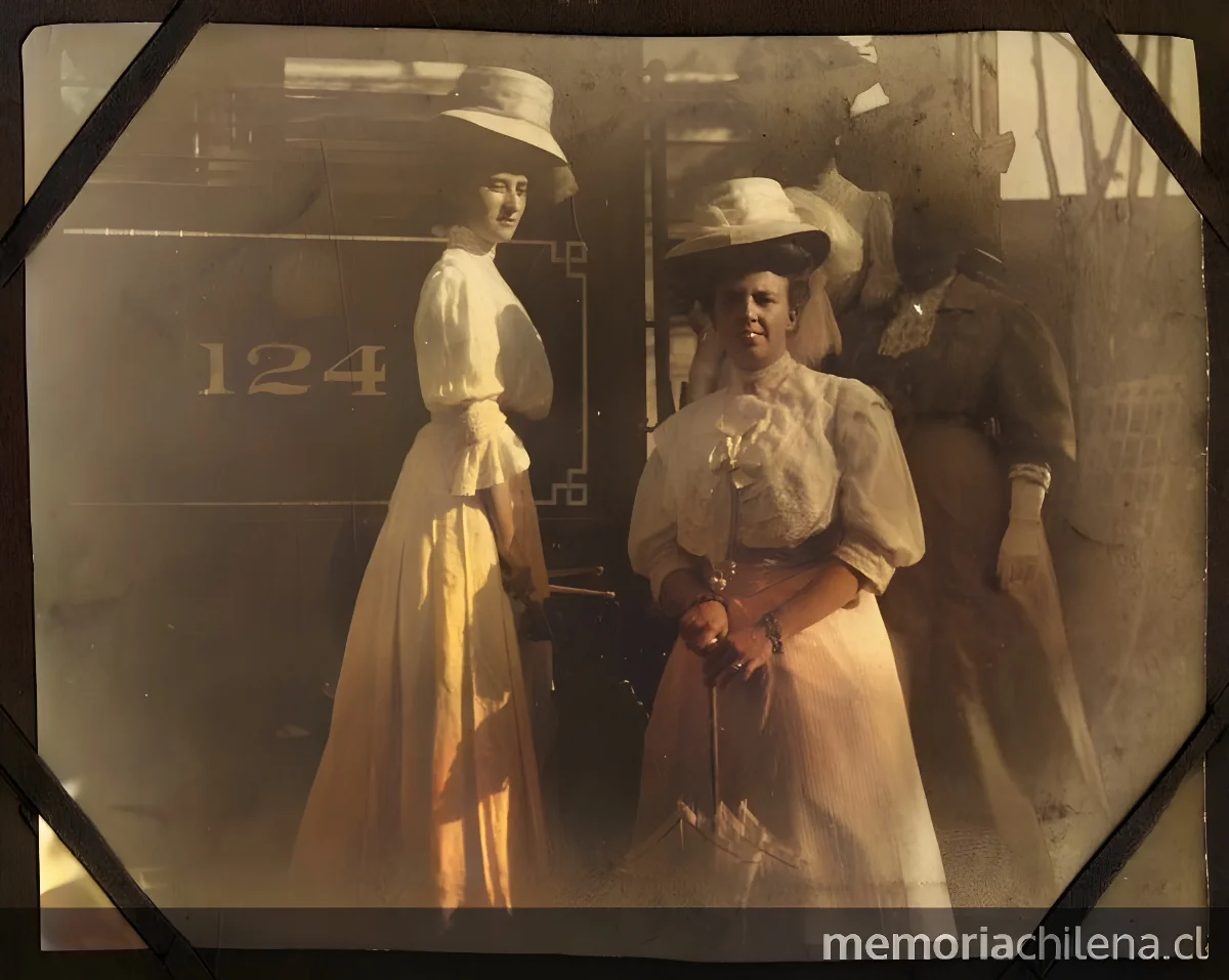 Cuatro señoras, con sombreros, posan en la escalera del tren, portan sombrillas — aprox. 1900 | Chile de Ayer