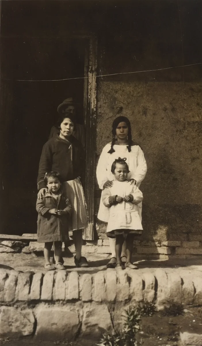 Familia ante muro de adobe con poste de madera — Década de 1940 | Chile de Ayer