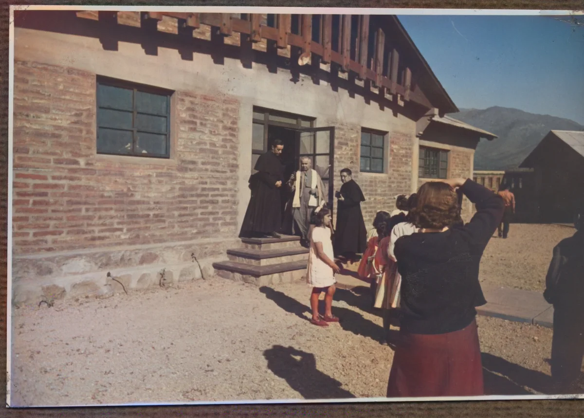 Mujer fotografiando a sacerdotes que visitan los "Colectivos" — Calle Larga — 1953 | Chile de Ayer
