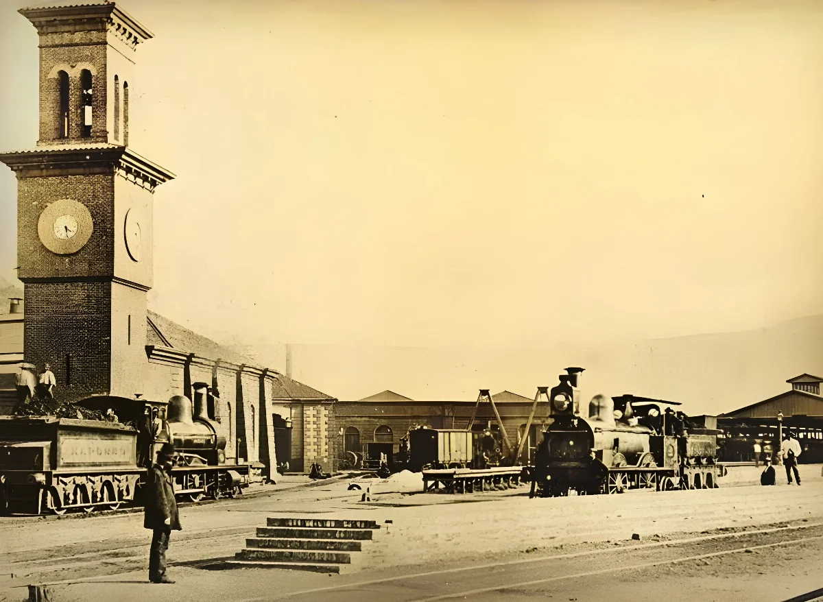 Estación ferroviaria con torre de reloj y locomotoras a vapor — aprox. 1890–1930 | Chile de Ayer