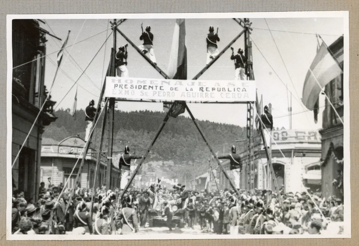 Arco del triunfo con escaleras y voluntarios de bomberos en homenaje a la visita del presidente. Gira a la zona austral del país de S.E. el Presidente de la Republica Don Pedro Aguirre Cerda — Lota — 1939 | Chile de Ayer
