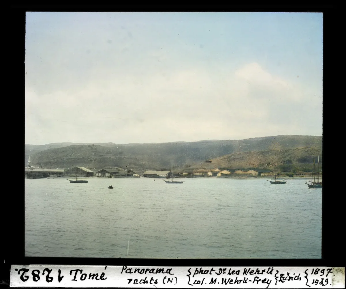 Panorama norte de Tome desde el mar, galpones junto a la playa y veleros en la bahia — aprox. 1897–1940 | Chile de Ayer