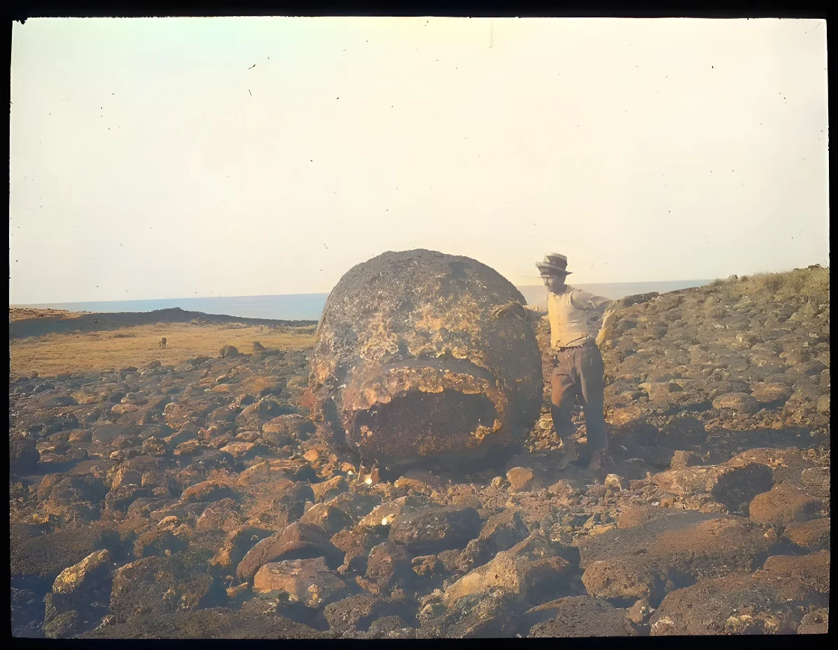 Chilean boy standing beside a large round stone used as part of a moai; Ahu Hekii, Oc,G.T.1623, Mana Expedition to Easter Island, British Museum — Isla de Pascua — 1914 | Chile de Ayer