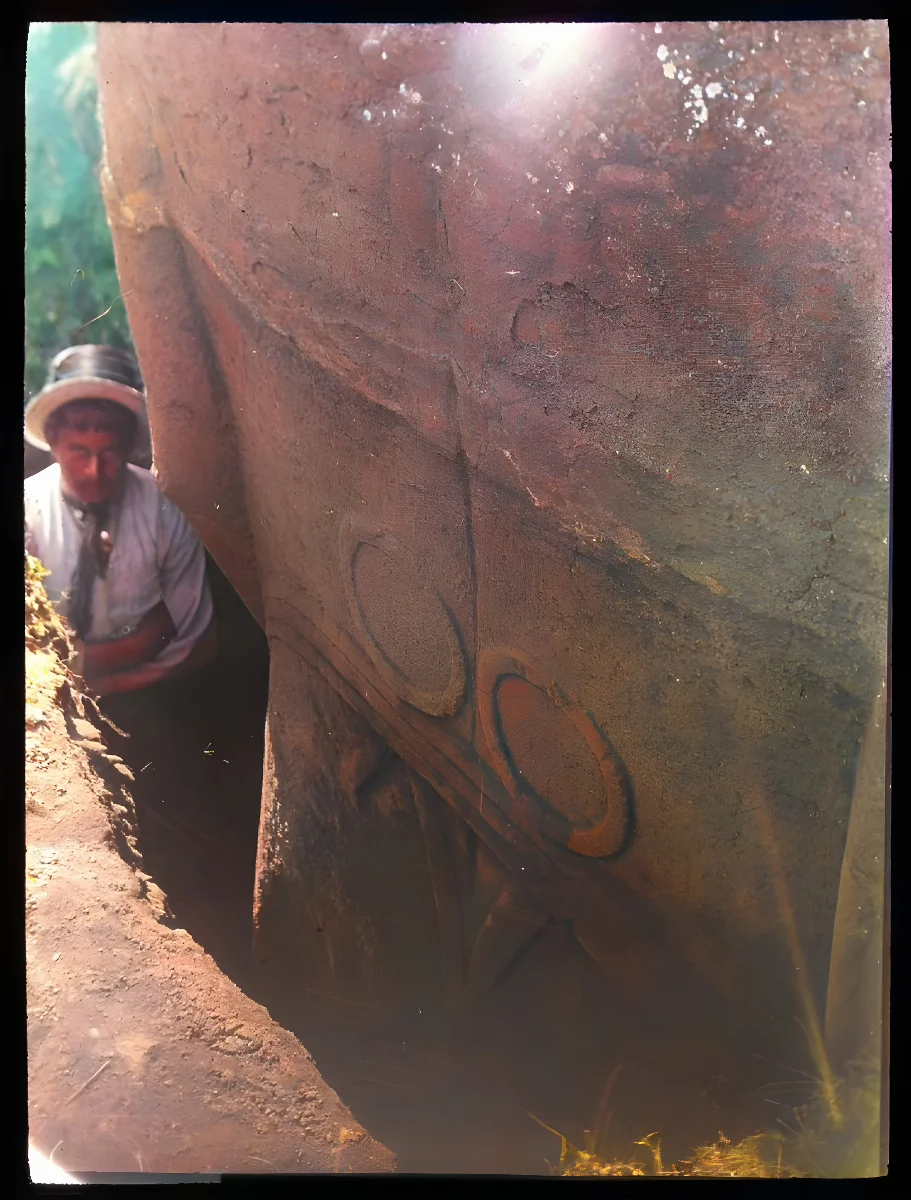 Close up view of the back of a moai excavated but still standing upright in the ground; a man is standing in the excavated gap beside the scultpure for scale; Rano Raraku, Oc,G.T.1476, Mana Expedition to Easter Island, British Museum — Isla de Pascua — 1914 | Chile de Ayer