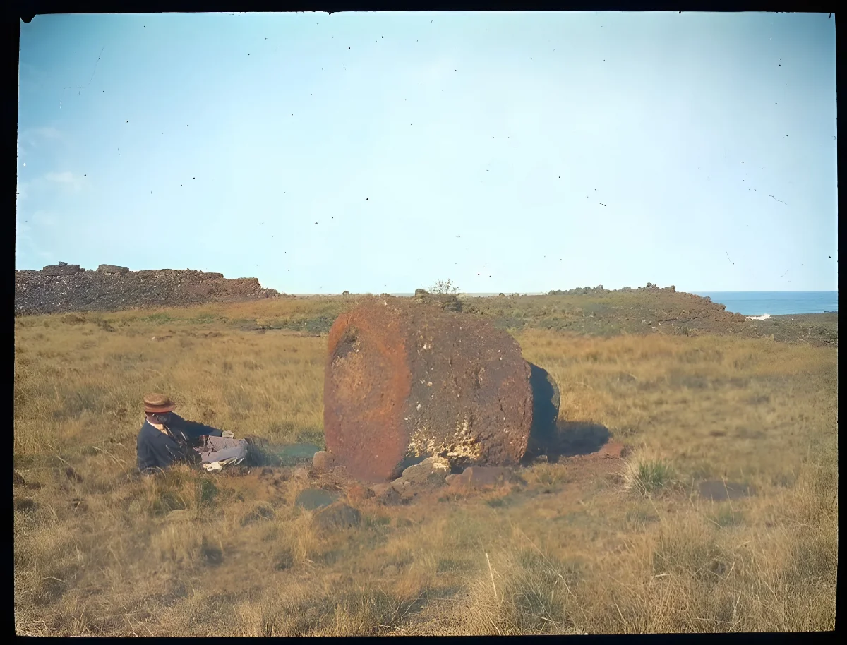 View of a large round stone used as part of a moai, with a White man lying on the ground beside it, for scale; Ahu Hekii, Oc,G.T.1624, Mana Expedition to Easter Island, British Museum — Isla de Pascua — 1914 | Chile de Ayer