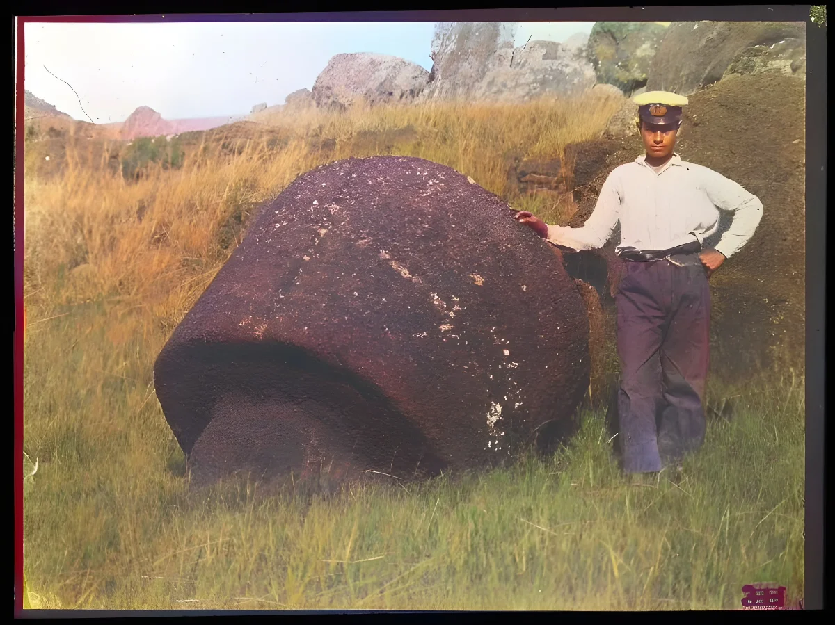 View of a round carved piece of stone, part of a moai, with a man standing beside the stone for scale, Oc,G.T.1499, Mana Expedition to Easter Island, British Museum — Isla de Pascua — 1914 | Chile de Ayer