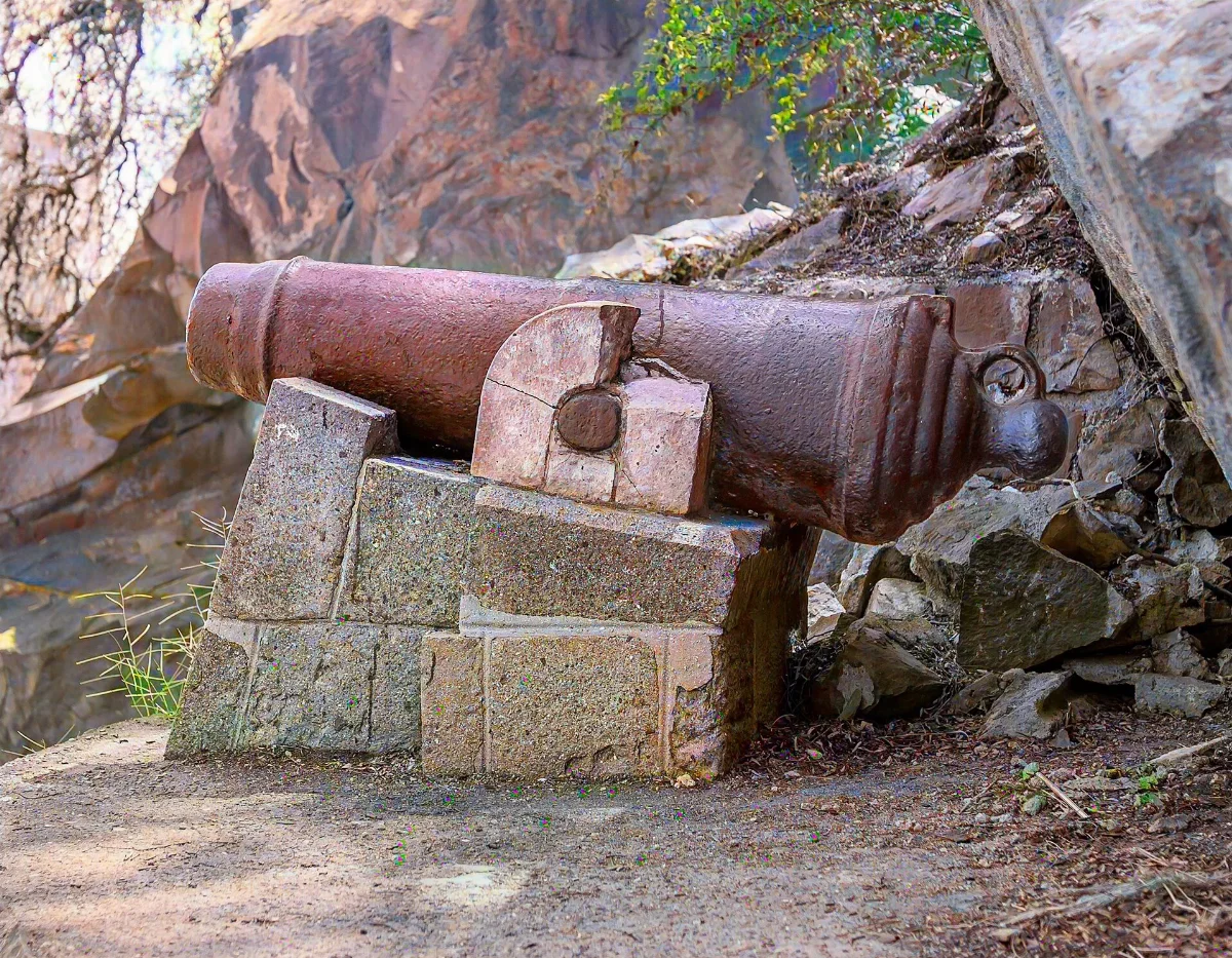 Cañón colonial de bronce sobre pedestal de piedra junto a la roca del Cerro Santa Lucía — aprox. 1880–1930 | Chile de Ayer