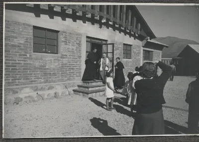 Mujer fotografiando a sacerdotes que visitan los "Colectivos" — Calle Larga — 1953 | Chile de Ayer